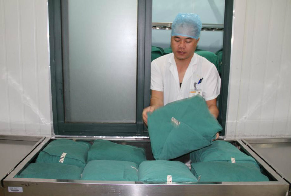 工作人员正在将消毒好的手术包从无菌间搬入专门运送无菌物品的车内，稍后将会送达手术室。